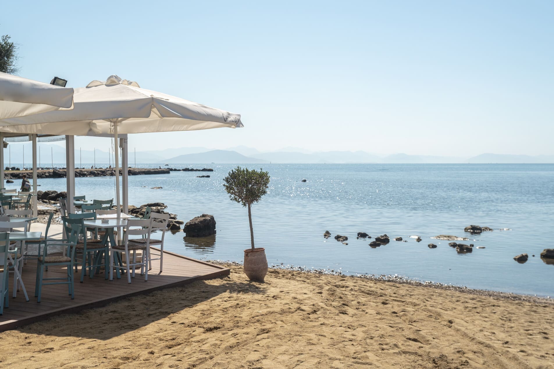 Terraza al aire libre de restaurante con mesas, sombrillas y decoración veraniega