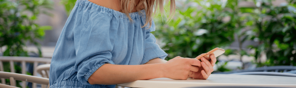Chica reservando mesa online con su teléfono